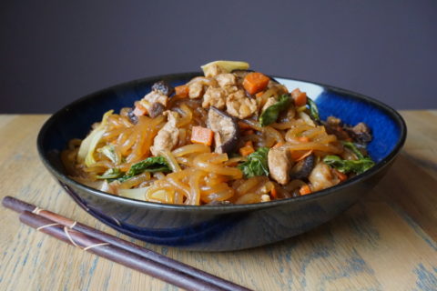 Vegan japchae met tempeh, shiitaken, wortel en spinazie