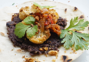 Vegan taco met refried beans, salsa en bloemkool