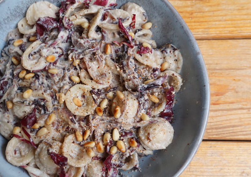 Vegan pasta met radicchio in een roomsaus met cashewnoten en pijnboompitten