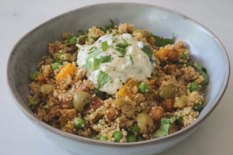 Vegan quinoa salade met pompoen, kikkererwten, doperwten , noten en amandelyoghurt