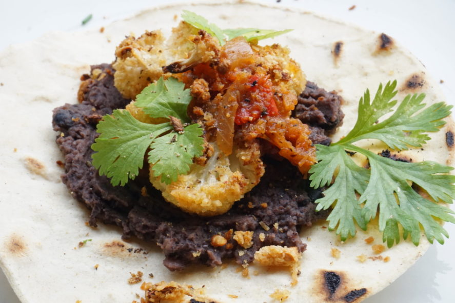 Vegan taco's, refried beans, salsa van gekarameliseerde ui en krokante bloemkoolstukjes